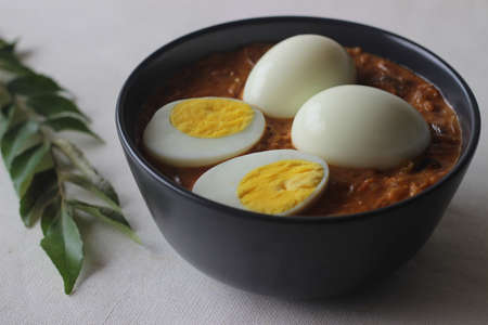 Kerala style spicy egg curry. Boiled egg in a spicy gravy of onions, tomatoes and spices. Locally known as egg roast. Shot on white background.の写真素材