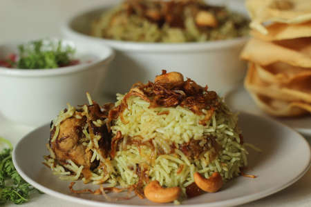 Green Biriyani. It is made with boiling basmati rice with green coriander chutney paste and spices and then layered with curried chicken and caramelized onions. A popular indian dish shot with papadsの写真素材