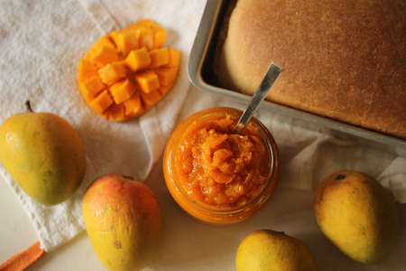 Home made alphonso mango jam with 3 ingredients. Mango pulp, sugar and lime juice. Alphonso mango is widely considered to be the tastiest in India. Shot with a wheat bread in the backgroundの写真素材