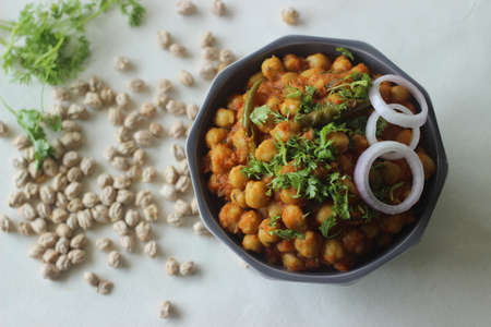 Chole masala. White chickpea gravy with tomatos onions and spices. Shot on white background