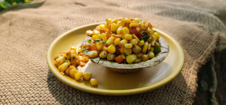 Steamed yellow sweet corn masala or corn chat prepared using butter, chat masala and lemon, favourite indian snack served on a palm leaf plate. Prepared by a street vendor at Mahabaleshwar, Indiaの写真素材
