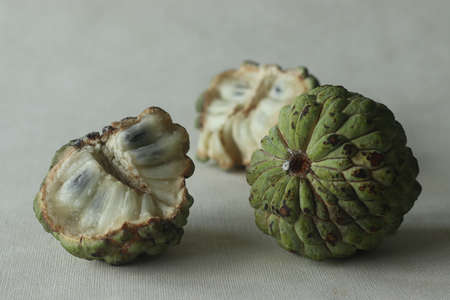 Custard apple, full and half cut slices. A Cherimoya family fruit with green and leathery skin. It...