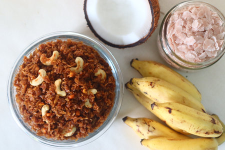 Flattened rice sweetened with jaggery. Aval Vilayichathu is a popular sweet snack of Kerala, made with beaten rice, coconut and jaggery. Shot on white background along with yellow bananas and coconutの写真素材
