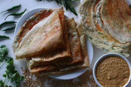 Jowar Dosa. A savoury crepe made of jowar flour. Golden crispy and crunchy dosa made with jowar flour, onion, cumin seeds, ginger, green chili and coriander leaves served with spicy coconut condimentsの写真素材