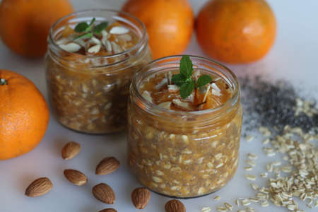 Chilled overnight oats and chia seeds in orange juice, served with chopped almonds and honey. Shot on white background. An easy and healthy breakfast.の写真素材