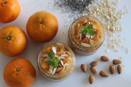 Chilled overnight oats and chia seeds in orange juice, served with chopped almonds and honey. Shot on white background. An easy and healthy breakfast.の写真素材