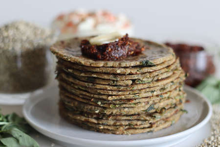 Bajra methi thepla. Indian flat bread made of pearl millet flour, fenugreek leaves, sesame seeds, yogurt and spices. Served with yogurt and spicy garlic condiments. Shot on white background.の写真素材
