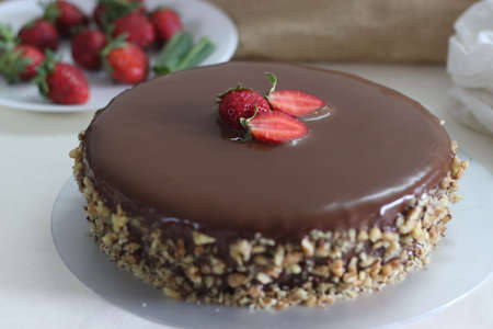 Chocolate cake with chocolate ganache and topped with walnut and fresh strawberries. Shot on white...