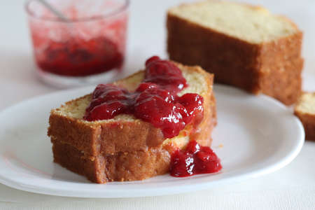 Sour cream pound cake along with a slice of pound cake with strawberry sauce spread. Shot on white...