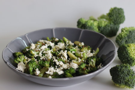 Broccoli with feta cheese. Sauteed broccoli florets sprinkles with served with crumpled feta cheese. Healthy dish to start the meal. Shot on white background.の写真素材