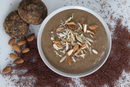 Whole ragi porridge. Whole grain finger millet porridge sweetened with jaggery, served with sliced almonds. Shot on white background.の写真素材