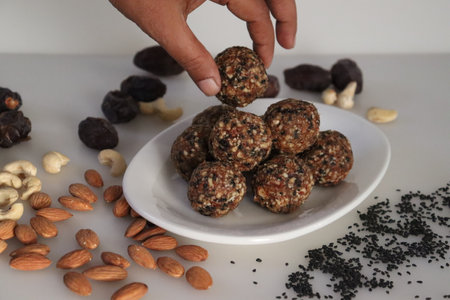 Sugar free dates and nuts ladoo. Healthy and protein rich energy balls in the shape of ladoos made from dates, almonds, cashew nuts and sesame seeds without adding any sugar. Shot on white backgroundの写真素材