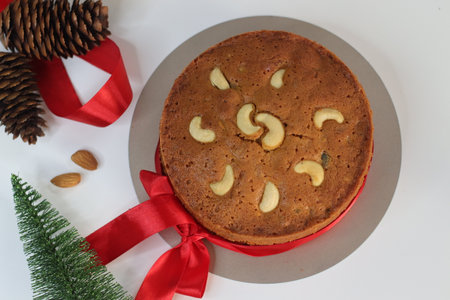 Christmas fruit cake with rum soaked raisins, as festive dessert is perfect for holiday parties and family gathering, featuring rich textures. Shot on white background with Christmas decorationsの写真素材