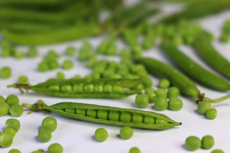 Open pea pods with scattered green peas and a bunch of green pea pods in the background. Showcasing fresh, organic produce. Perfect for food blogs, recipes, healthy eating, and nutrition contentの写真素材