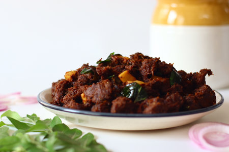 Kerala Beef Fry. A flavorful South Indian dish made by marinating beef with spices, slow-cooking it with onions, garlic, curry leaves, and garnishing with crispy coconut flakesの写真素材