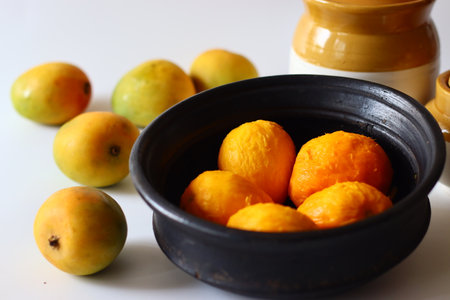 Peeled ripe mangoes in an earthen pot, ready for cooking in a Kerala style curry with yogurt,...