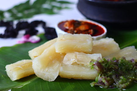 Boiled tapioca, kappa served on banana leaf with spicy green chili chutney and vibrant Kerala style red fish curry, meen curry. A wholesome South Indian meal perfect for traditional cuisine visualsの写真素材