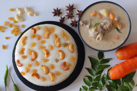 Kerala style mutton stew paired with vattayappam, a steamed rice cake topped with raisins and cashews. A festive South Indian meal styled with spices, curry leaves, and vibrant ingredientsの写真素材