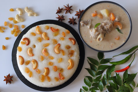 Kerala style mutton stew paired with vattayappam, a steamed rice cake topped with raisins and cashews. A festive South Indian meal styled with spices, curry leaves, and vibrant ingredientsの写真素材