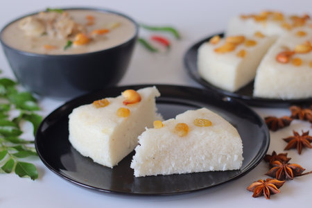 Kerala style vattayappam topped with golden raisins, sliced and served with mutton stew in coconut milk gravy. Styled with curry leaves, chilies, and star anise for a festive South Indian breakfast.の写真素材