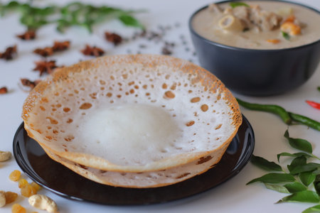 Kerala style appam with mutton stew in coconut milk gravy, styled with curry leaves, spices, and cashews. A traditional South Indian breakfast perfect for festive, cultural, and culinary themes.の写真素材