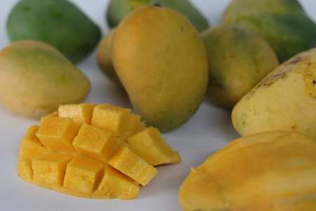 Nayab mangoes presented whole and cubed on a clean surface, featuring vibrant yellow orange flesh...