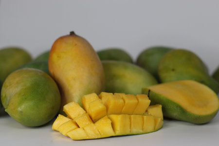 Raseeli mango presented in hedgehog cut and halved style, featuring ripe yellow flesh and green...