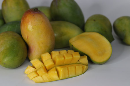 Raseeli mango presented in hedgehog cut and halved style, featuring ripe yellow flesh and green...