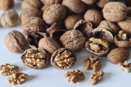 Walnuts in mixed shell and cracked style, featuring whole nuts and exposed kernels. Commonly enjoyed...
