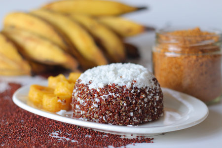 Red quinoa puttu layered with grated coconut, served with ripe banana and jaggery powder in a glass jar. A gluten free Kerala style breakfast combining quinoa with traditional South Indian flavorsの写真素材