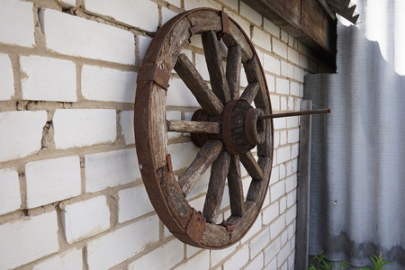 Wooden wheel from a cart against a rural log hutの写真素材