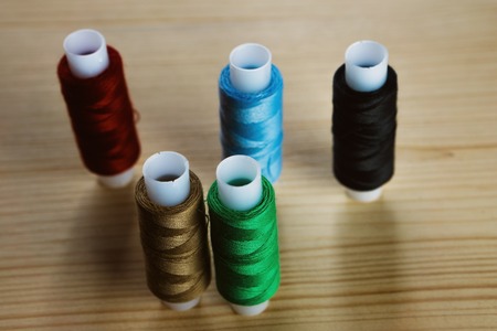 5 coils with a thread on a wooden tableの写真素材