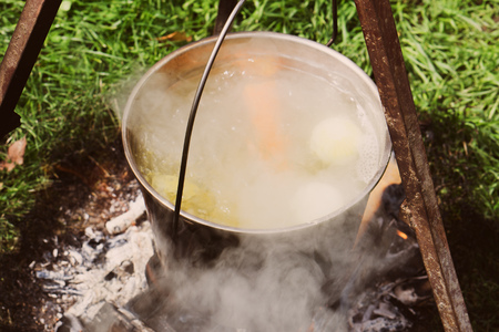 A kettle with boiling soup over a fire on a bright dayの写真素材