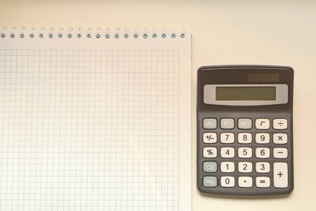 White notebook and digital calculator on a white table, isolate.の写真素材