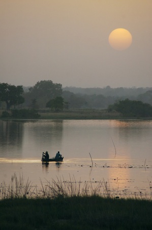 African fishermen checking nets on a lake at sunsetの写真素材