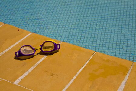 Pair of swimming goggles lying beside a poolの写真素材