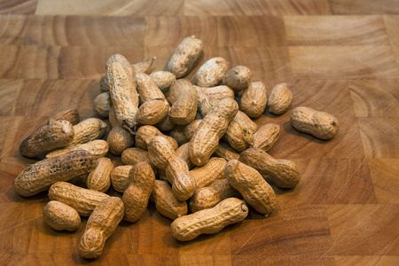Peanuts in their shells resting on a wooden chopping board