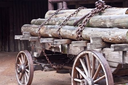 Old wagon with logs secured with chainsの写真素材