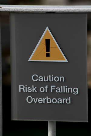 Caution risk of falling overboard sign, on ferry heading towards the Isle of Wightの写真素材