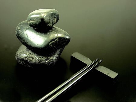 Black hot stones and black chopstick on black backgroundの写真素材
