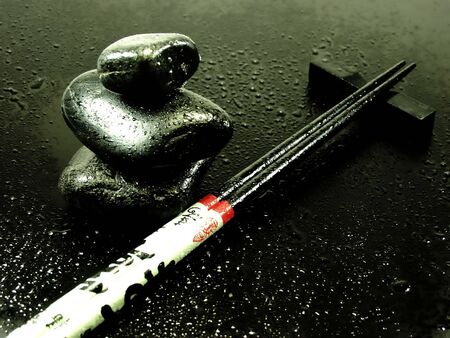 hot stones on black whit chopsticks and water dropsの写真素材