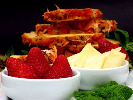 Fruit plate with strawberries and pineapple on black backgroundの写真素材