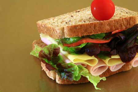 wholebread sandwich with ham and cheese on brown backgroundの写真素材