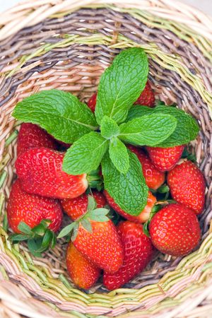 a wooden basket with red strawberry and green mint leavesの写真素材