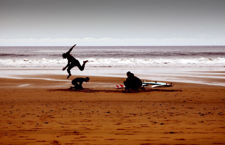 some young surfers play in the sand at sunsetの写真素材