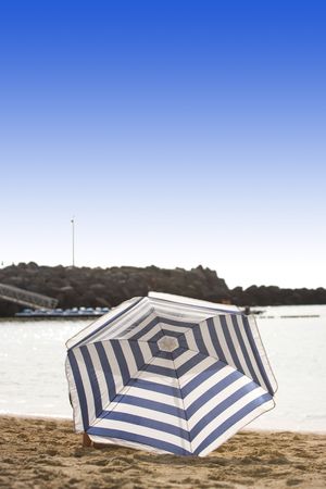 white and blue parasol on desert beachの写真素材