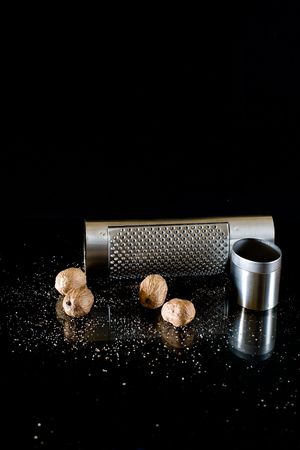nutmeg and silver grater on black backgroundの写真素材