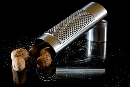 nutmeg and silver grater on black backgroundの写真素材