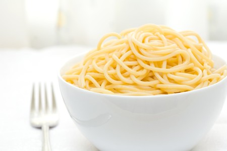 white bowl with boiled spaghetti and silver forkの写真素材
