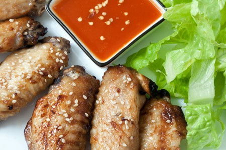 Grilled chicken wings with hot pepper sauce and saladの写真素材